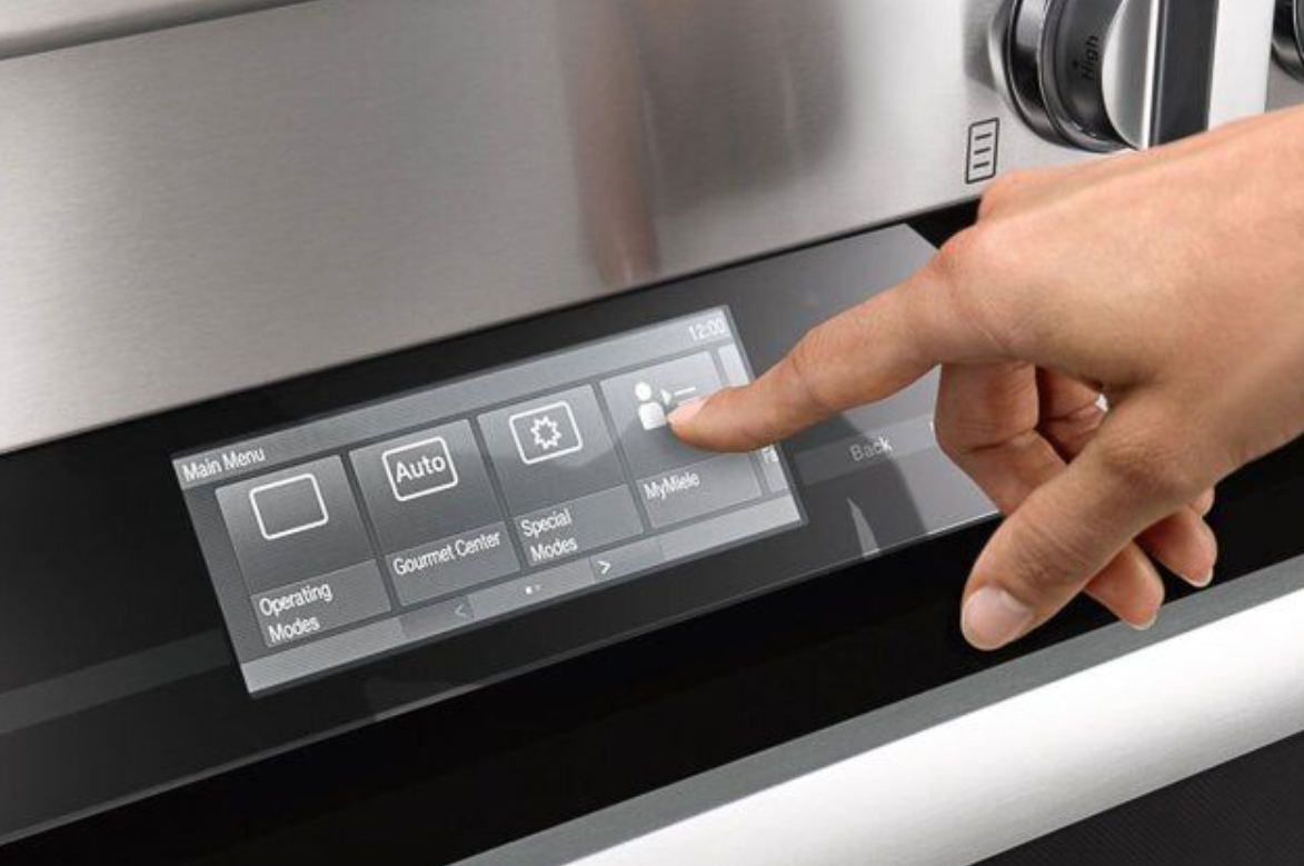 Flush touch pad on an oven with a hand pushing the far left button