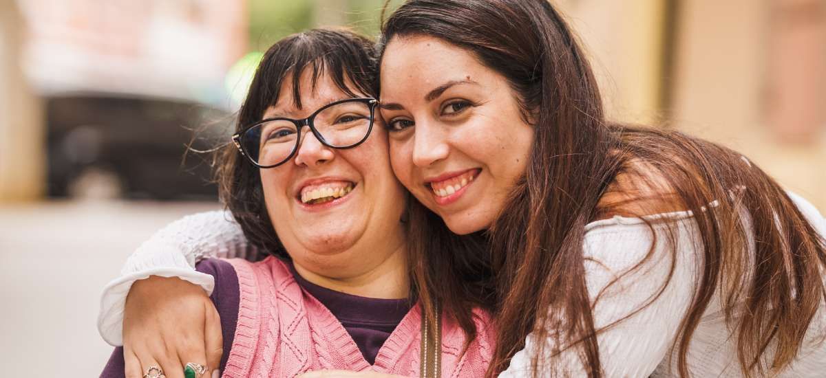 Two ladies embracing and smiling