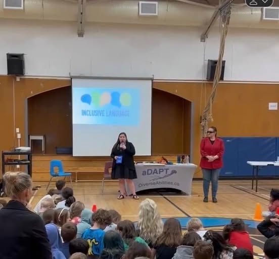 Youth aDAPT school assembly with Gina standing in front of the students in a gym.