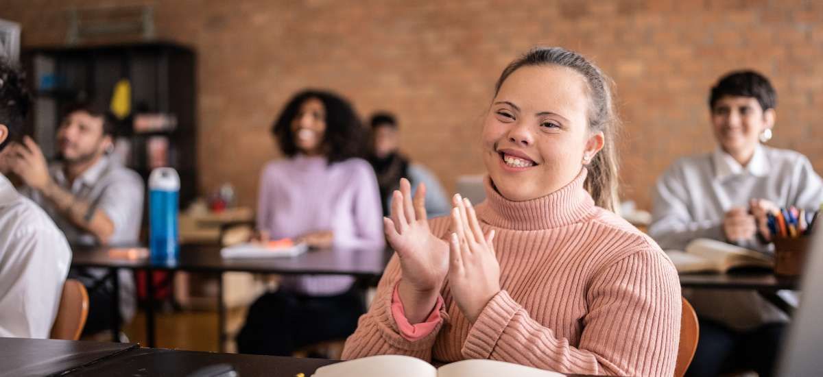 Post-secondary disabled student smiling and clapping her hands in class along with her classmates