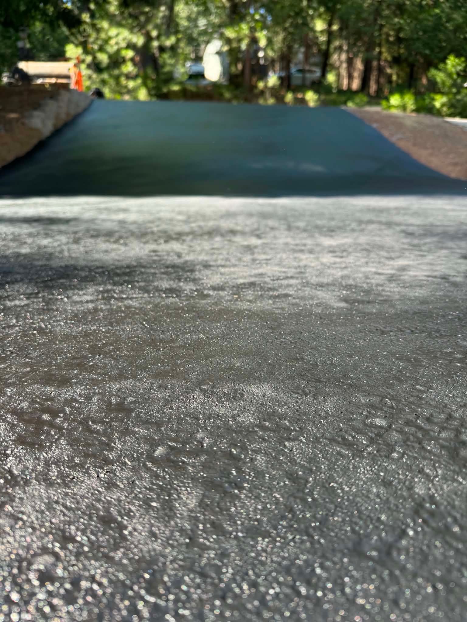 Sunlit outdoor ramp with textured pavement and trees in the background
