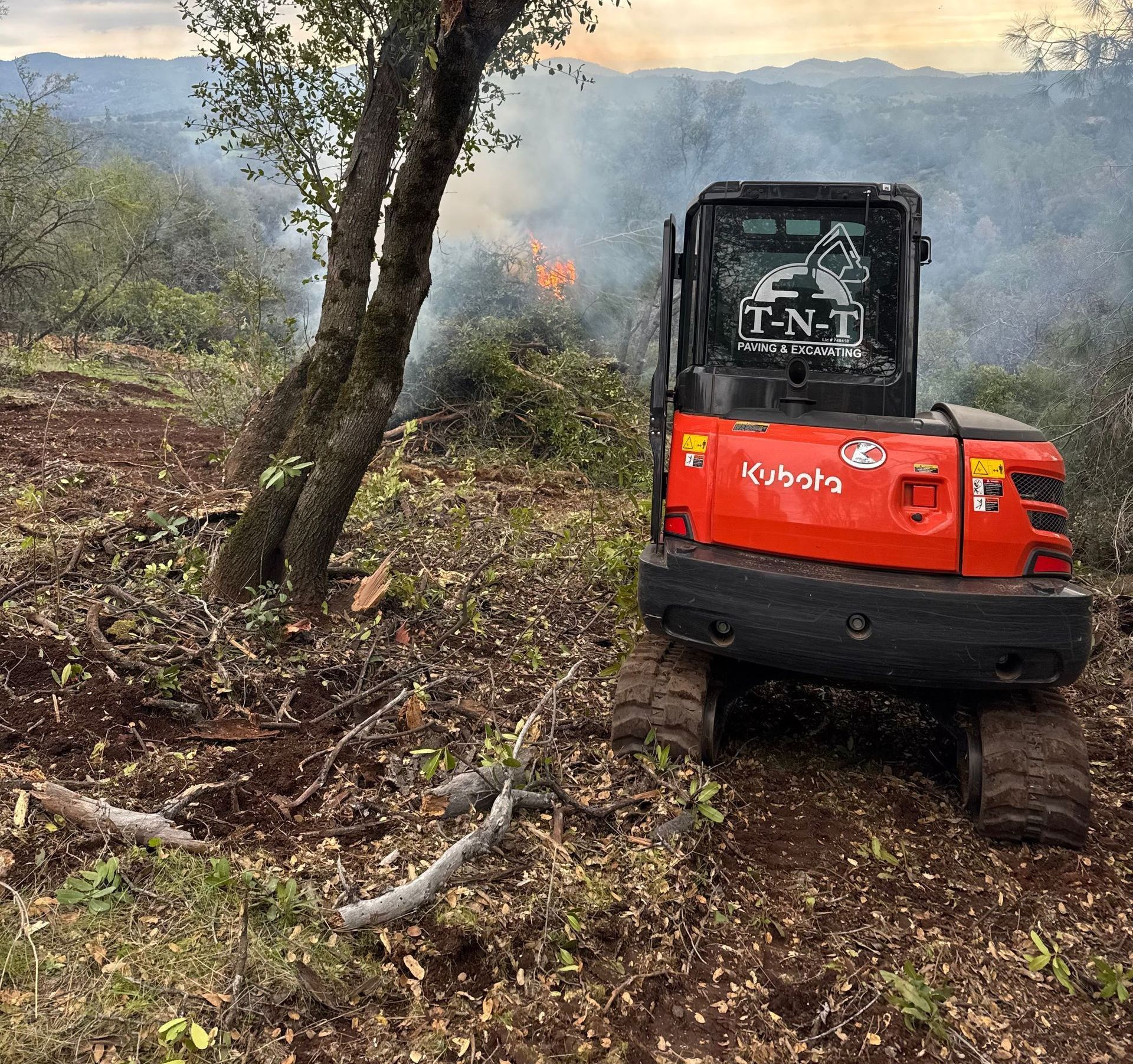 A red kubota excavator is parked in a field