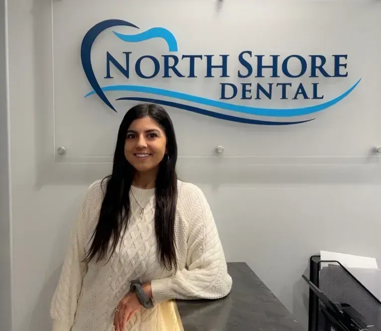Woman standing in front of North Shore Dental sign indoors