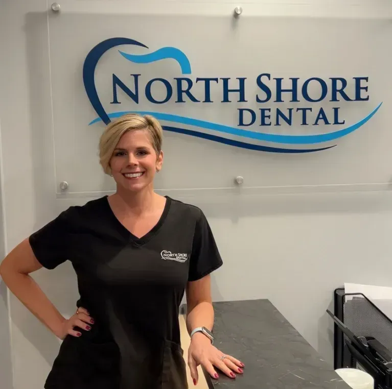 Woman standing in a dental office lobby beside a North Shore Dental sign