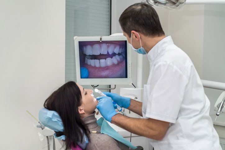 Dentist examining a patient’s teeth on a monitor in a bright dental clinic
