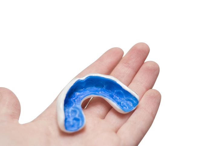 Blue mouthguard resting on a person's open palm