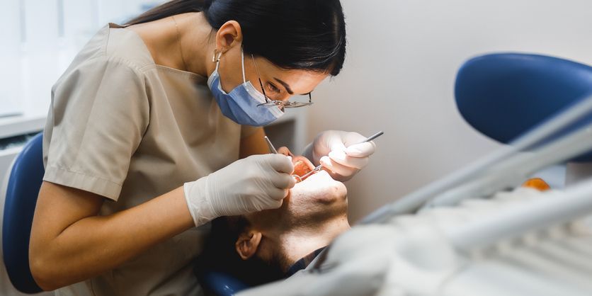 Dentist treating a patient in a dental chair with bright overhead light and tools