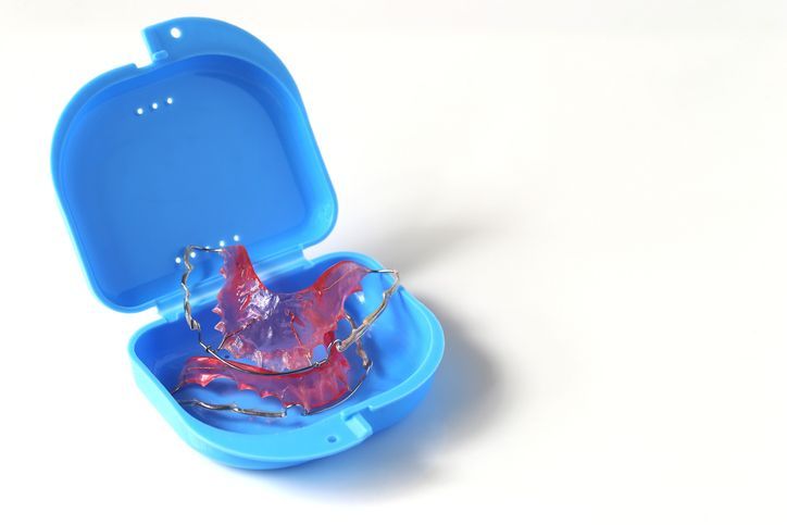 Blue retainer case with clear orthodontic aligner inside on a white background