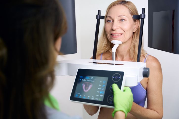 Woman at an optometry exam using a digital vision testing device while smiling at the technician