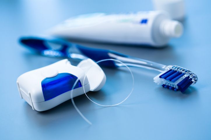 Blue-and-white toothbrush with a tube of toothpaste on a blue surface