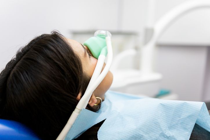 Patient lying back in a dental chair wearing a breathing mask and blue bib