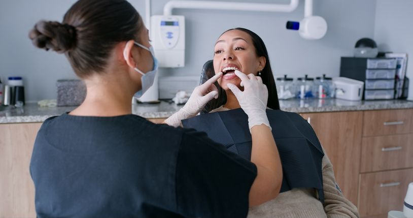Dentist examining a patient’s mouth in a modern clinic, with the patient reclining in a chair.