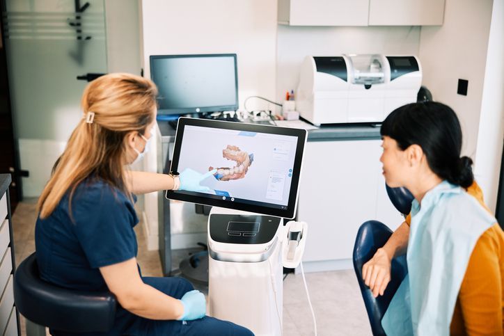 Dentist showing tooth shade samples to a smiling patient wearing a maroon scarf