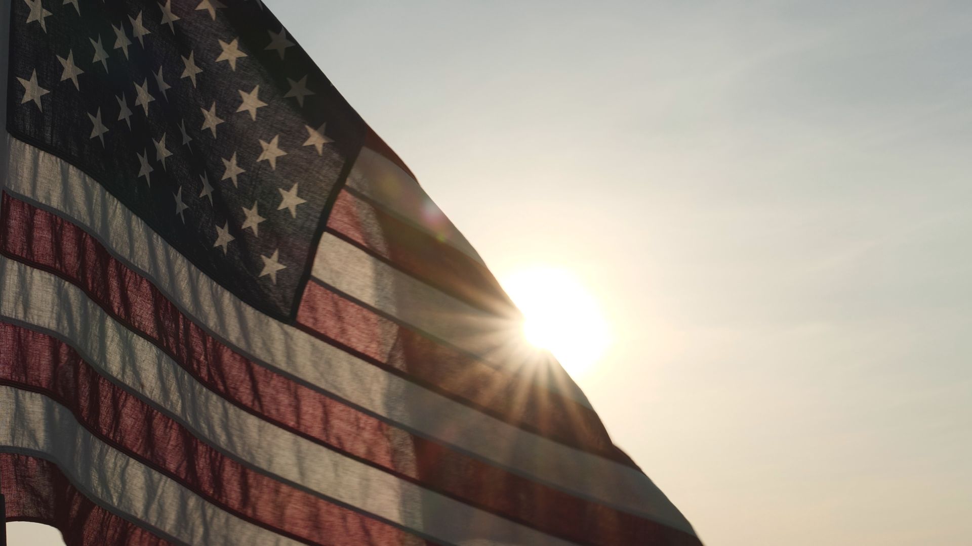 American flag waving with the sun shining through.