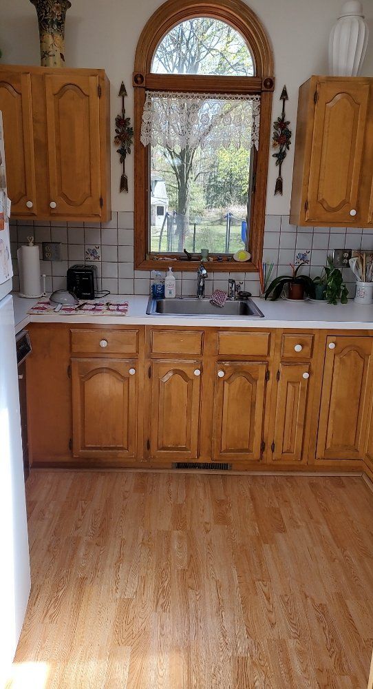 A kitchen with wooden cabinets , a sink , and a window.
