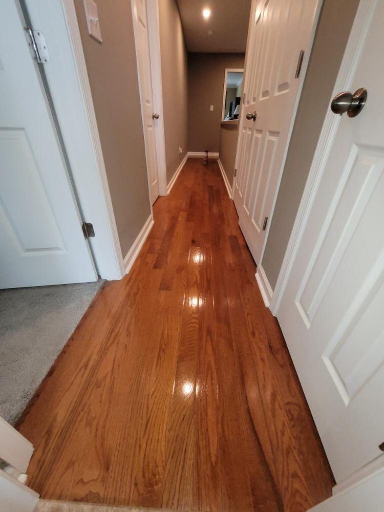 A hallway with hardwood floors and white doors in a house.