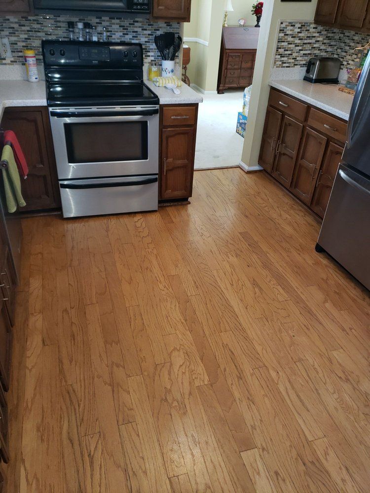 A kitchen with hardwood floors , stainless steel appliances , and wooden cabinets.