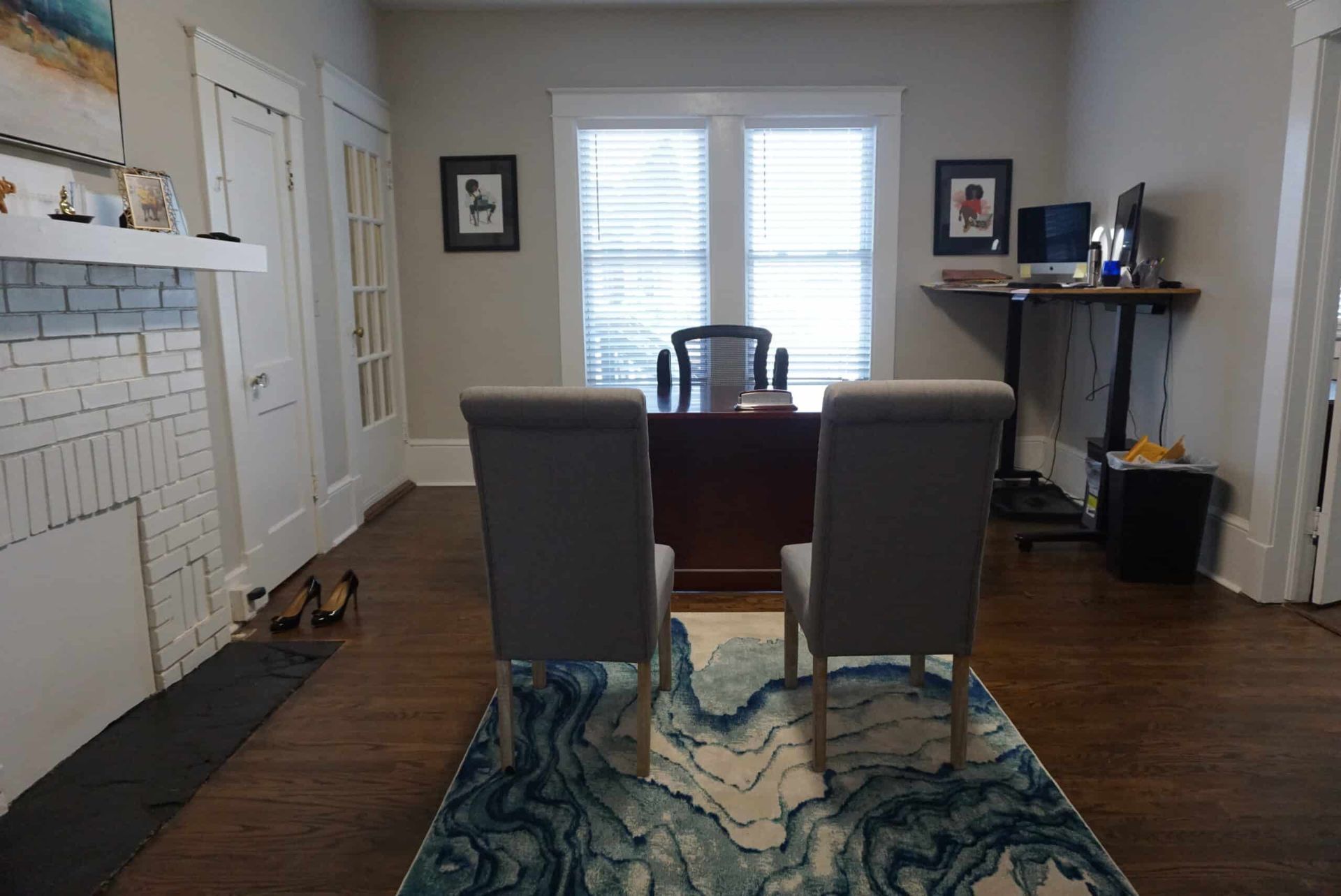 Living room with two chairs, desk, rug, and fireplace, seen from the front door