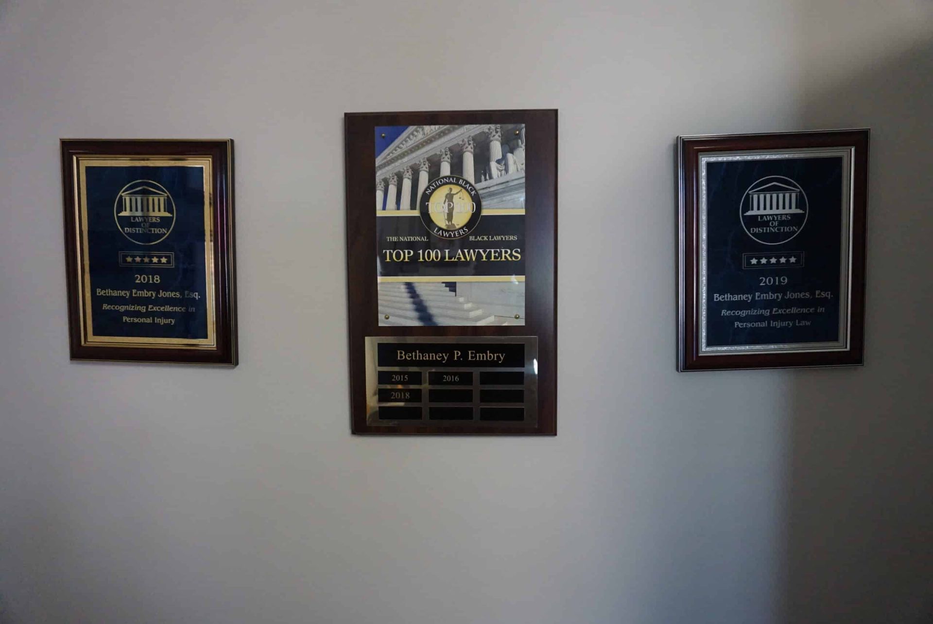 Three framed wall plaques with gold accents on a white wall