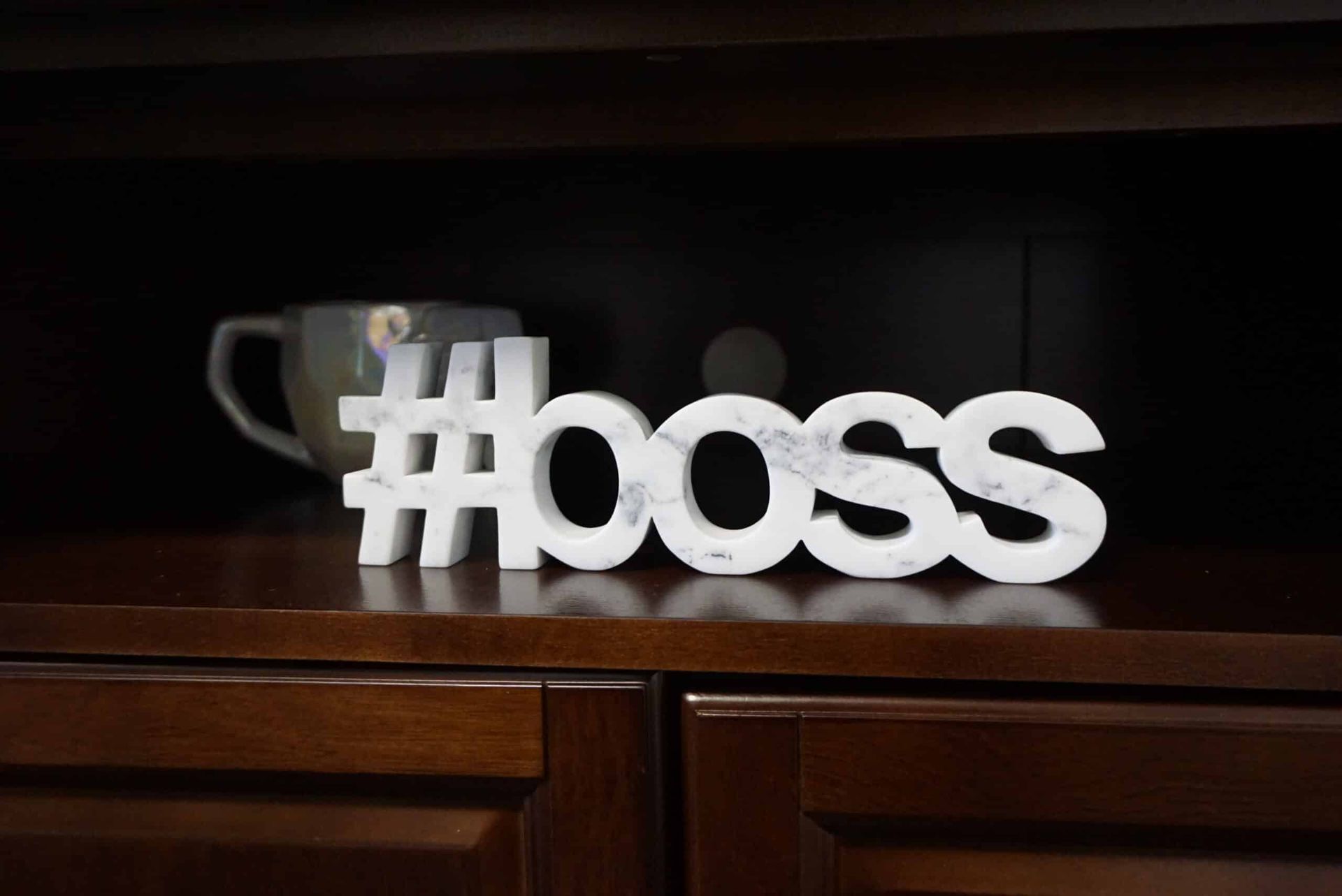 White “#boss” sign on a dark wooden shelf