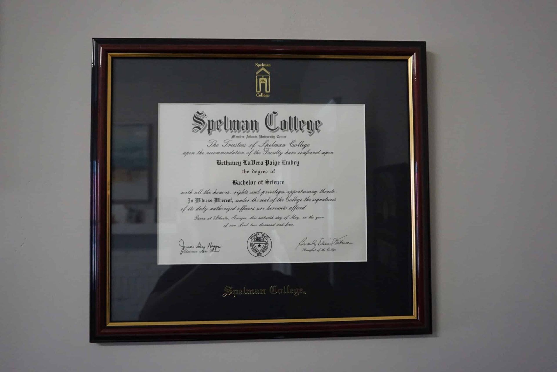 Framed Springfield College diploma on a wall, with a gold-trimmed black mat and wooden frame