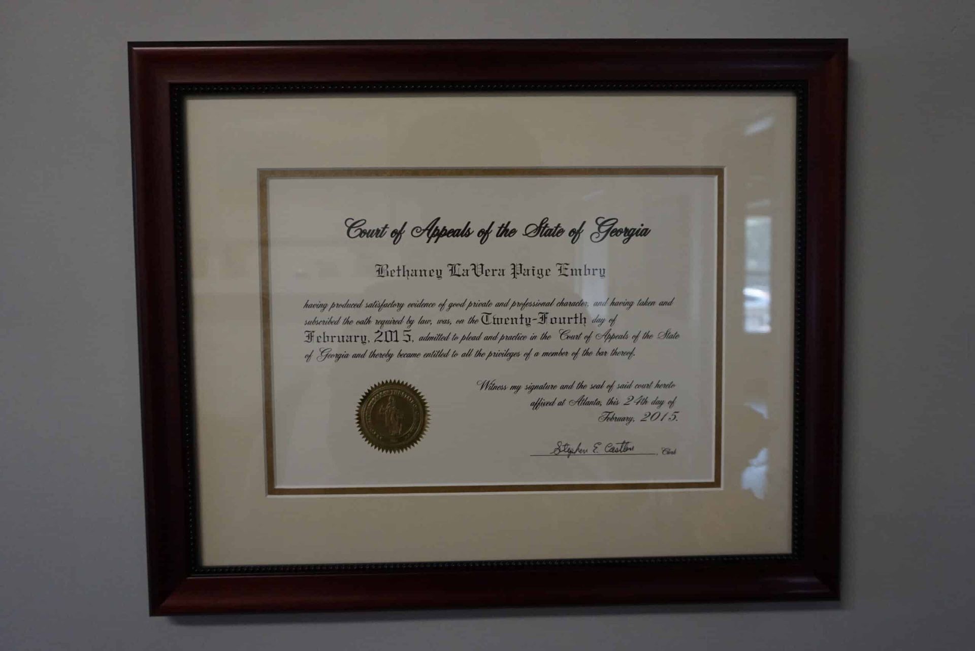 Framed certificate with gold seal in a dark wood frame on a wall