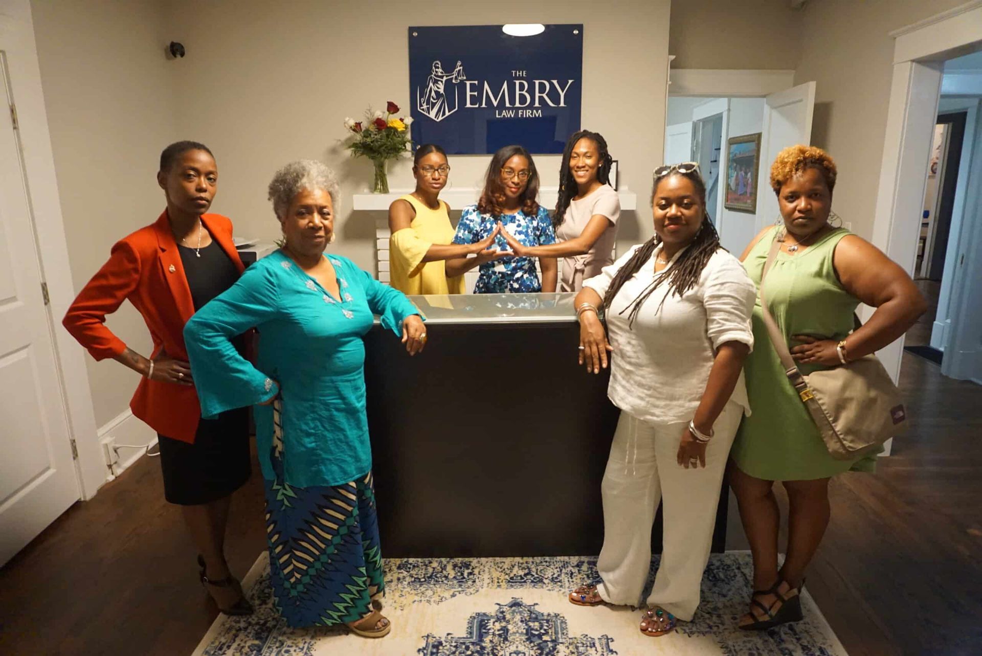 Six people pose behind a podium in a lobby with an Embry sign.