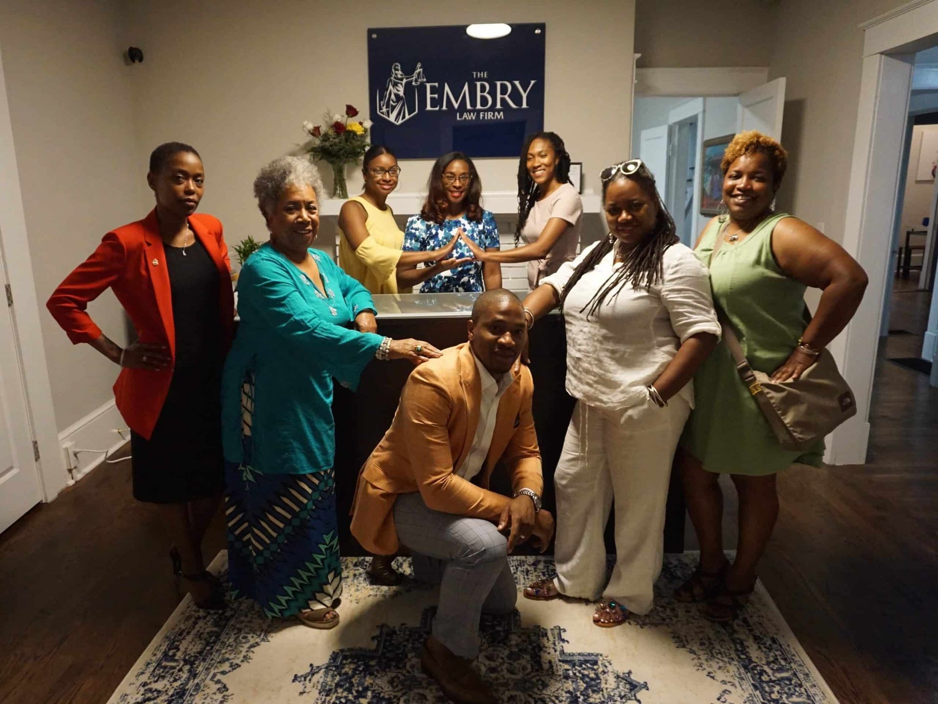 Group posing in an office lobby with an Emory sign, smiling and dressed in formal attire.
