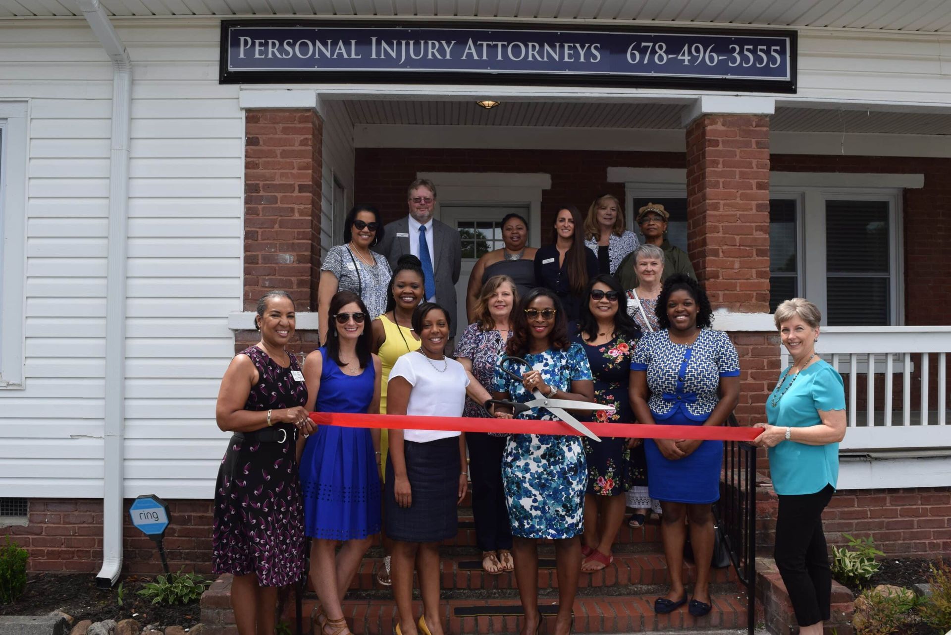Group of people posing with a ribbon outside Personal Injury Attorneys office