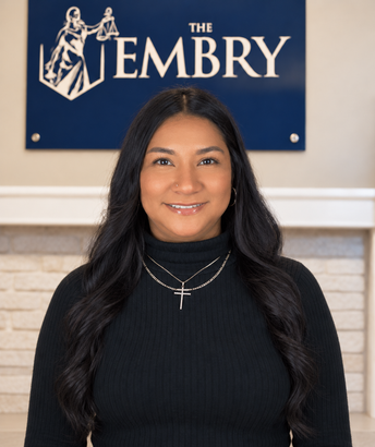Portrait of a woman standing indoors in front of a sign reading “The Embry”