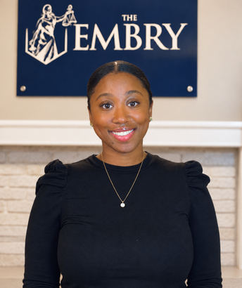 Woman smiling in black top standing in front of The Embry sign