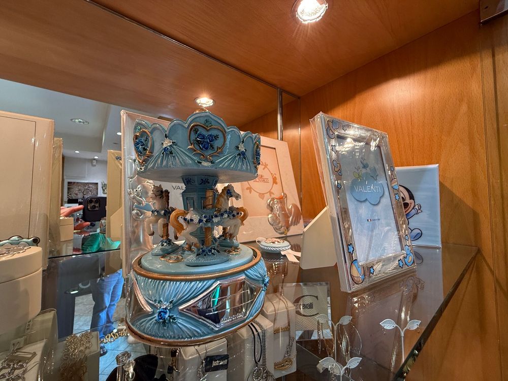 Una giostra decorativa blu è esposta in una stanza rivestita di pannelli in legno, con accanto un'opera d'arte incorniciata.