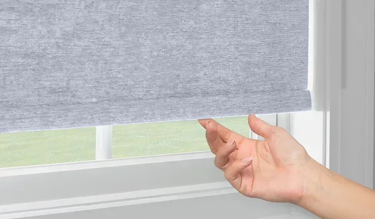 Hand lifting a gray window blind to let light in