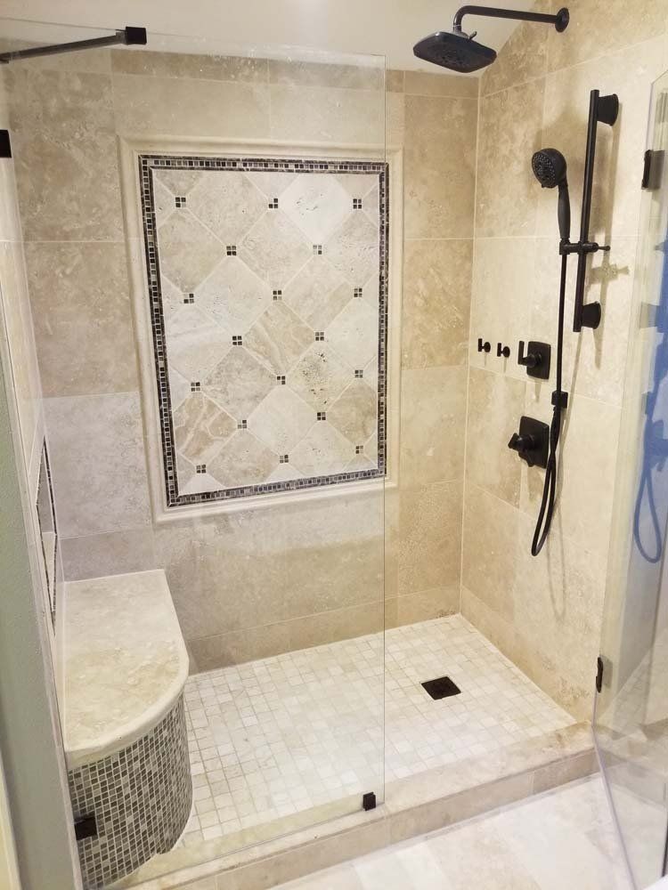 A tiled walk-in shower with a seat. Beige walls and white floor tiles. Black shower fixtures.