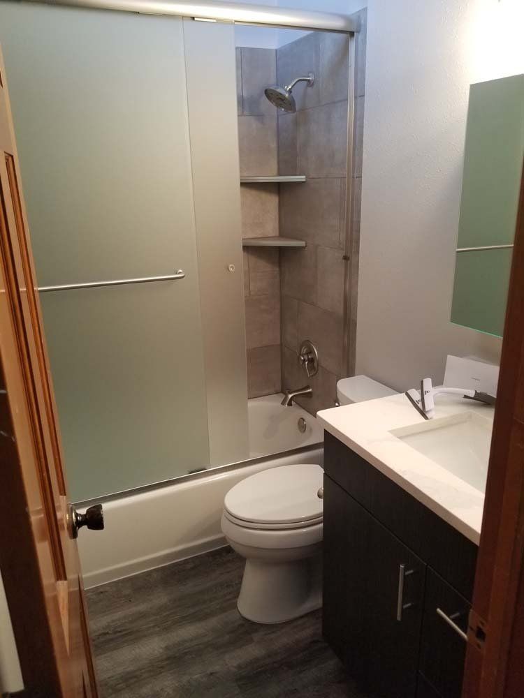 Bathroom with frosted glass shower door, dark wood vanity, toilet, and gray walls.