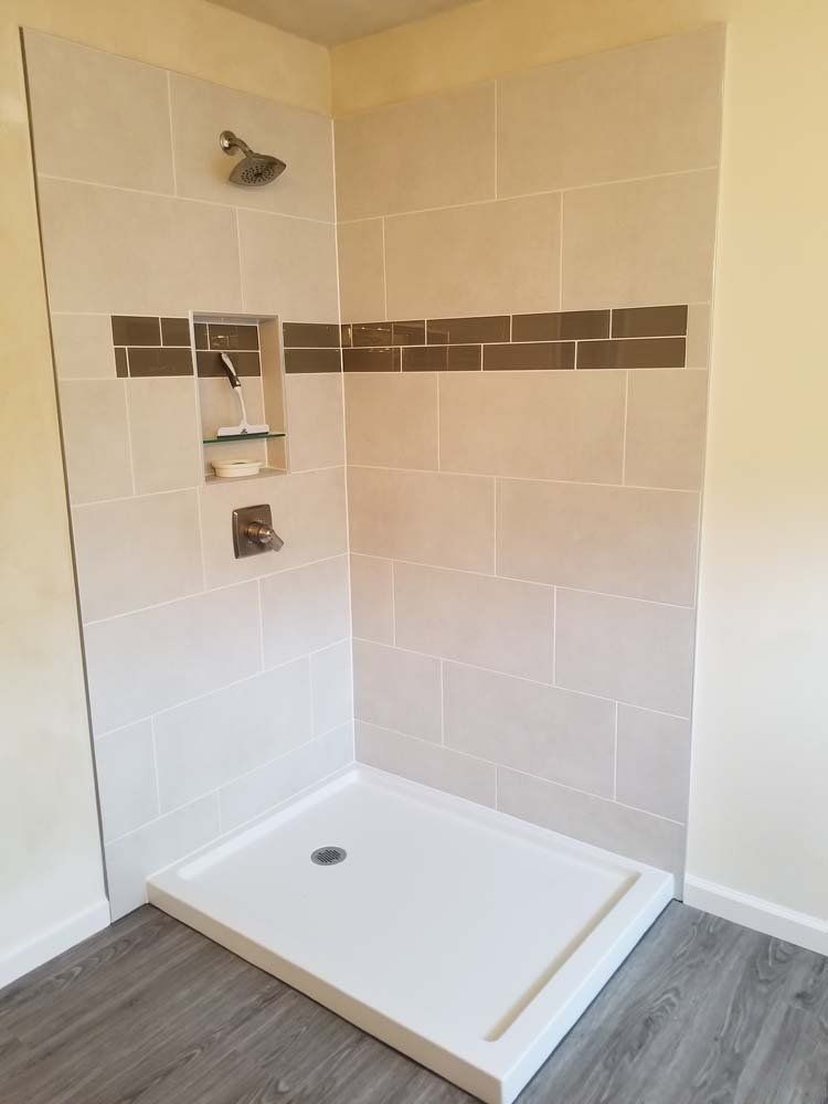 Tiled shower stall with a white base and a brown accent stripe.