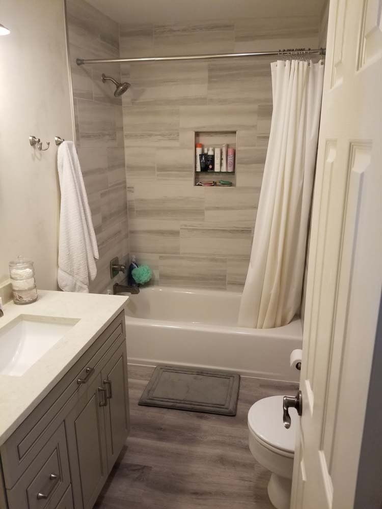 Bathroom with gray vanity, tub/shower with tiled wall, and wood-look flooring.