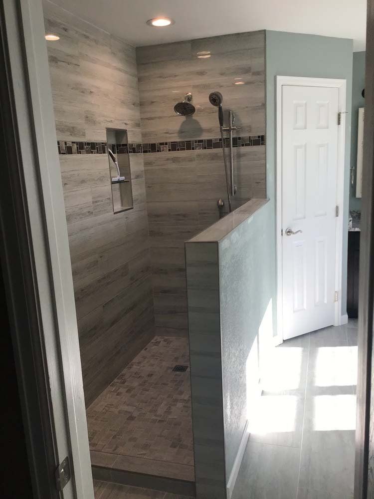 Modern bathroom with tiled shower, glass partition, and white door.
