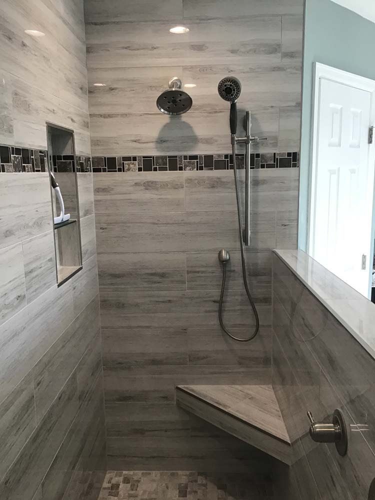 Tiled shower with handheld and rainfall shower heads, built-in bench, and a niche for toiletries.