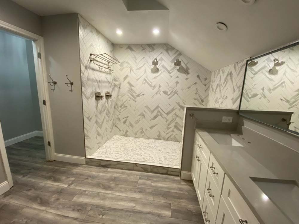 Bathroom with walk-in shower, gray walls, white cabinets, and wood-look flooring.
