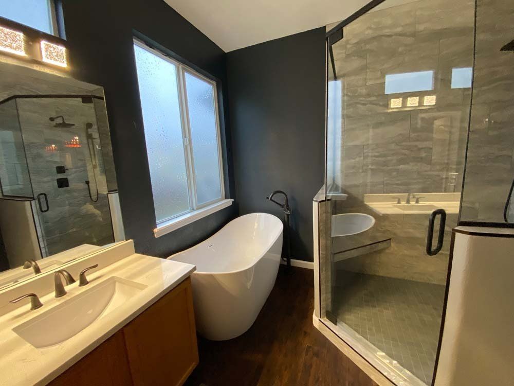 Modern bathroom with a freestanding tub, glass shower, and dark gray walls.