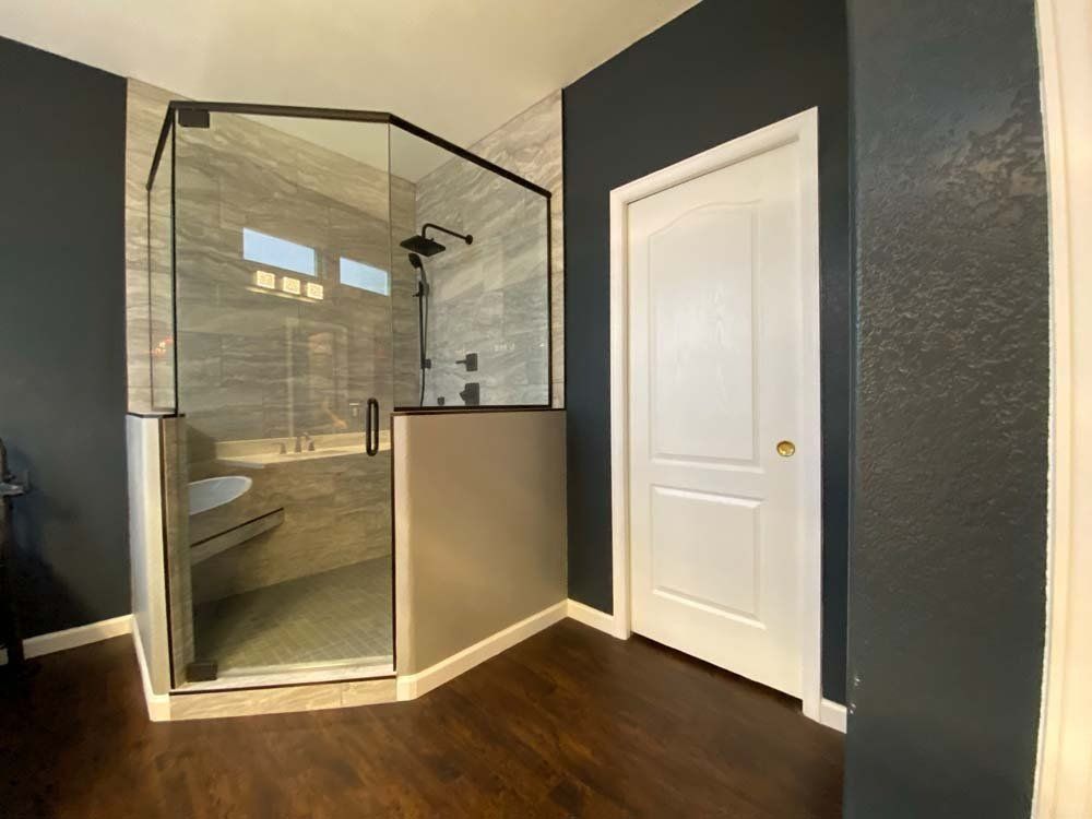 Bathroom with dark walls, glass shower enclosure, and white door.
