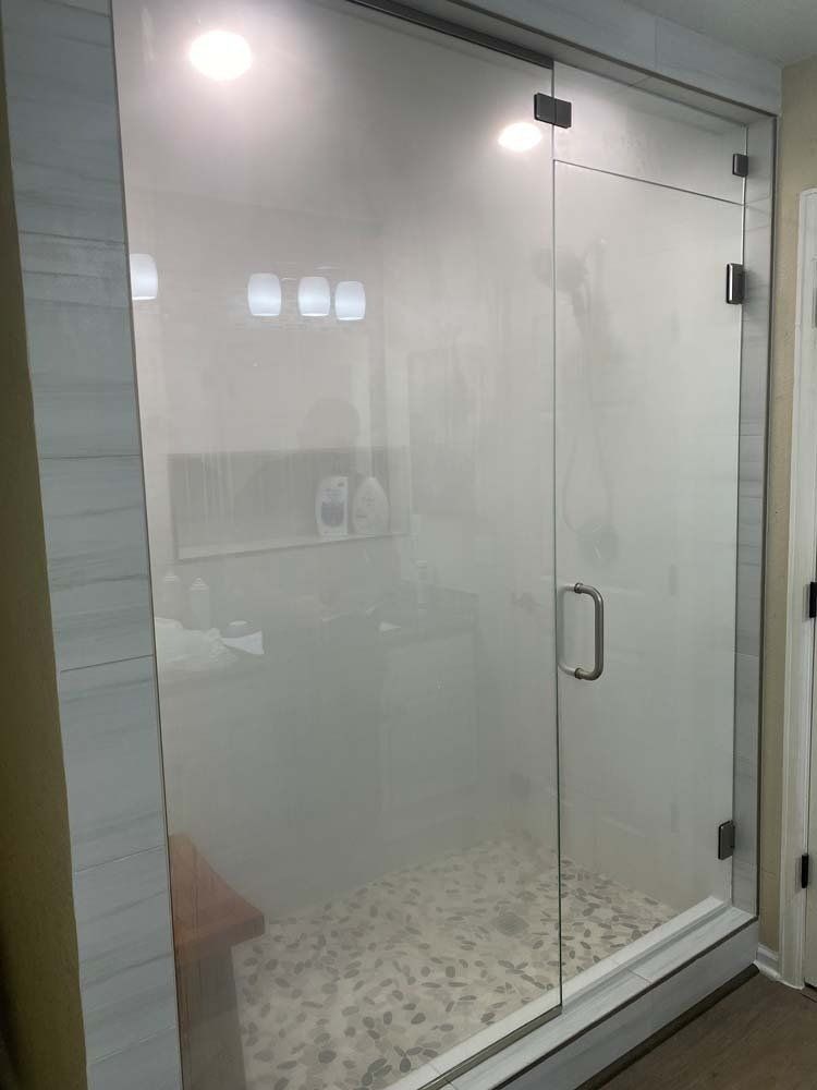 Glass shower enclosure with door, tile walls, and stone floor.