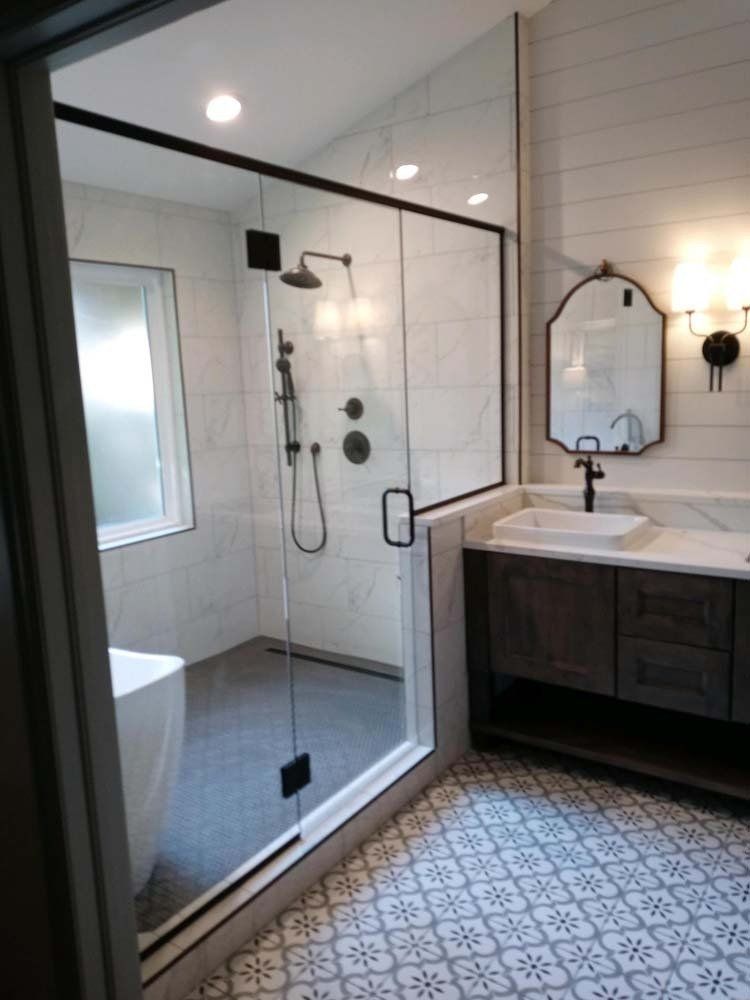 Modern bathroom with a glass shower enclosure, vanity, and patterned tile flooring.
