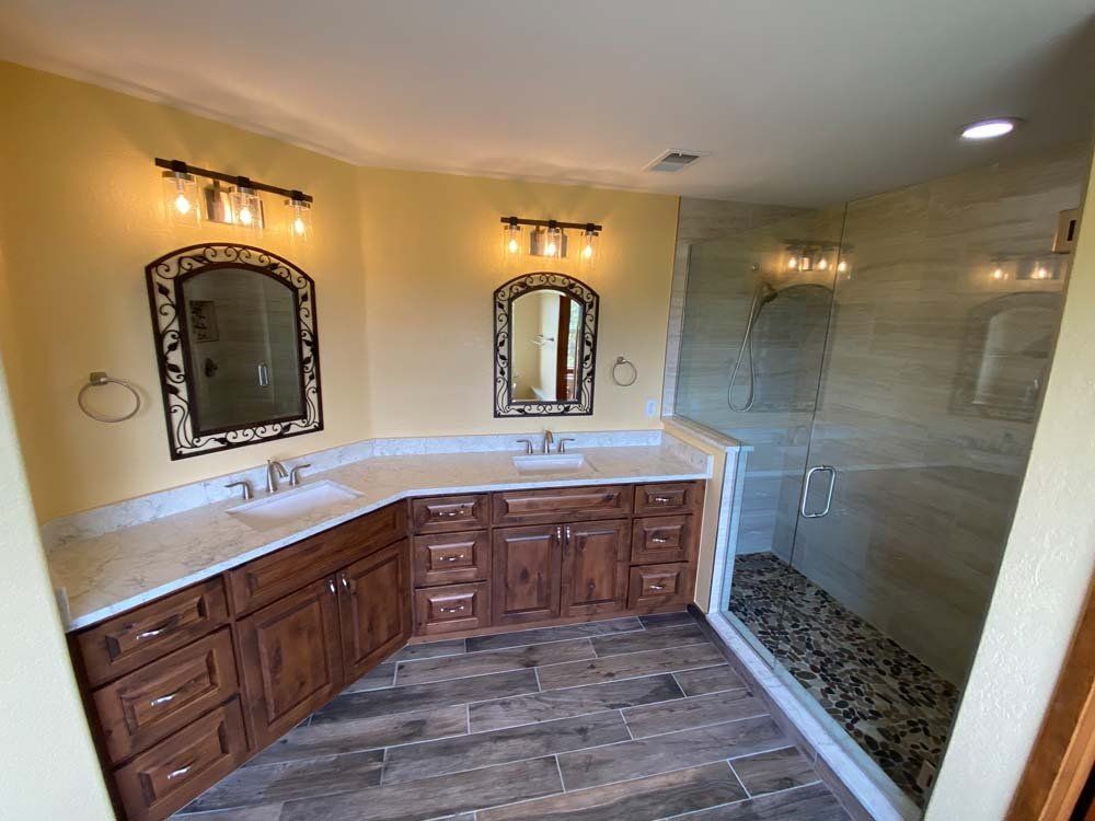 Bathroom with corner vanity, two mirrors, and a shower with pebble floor.