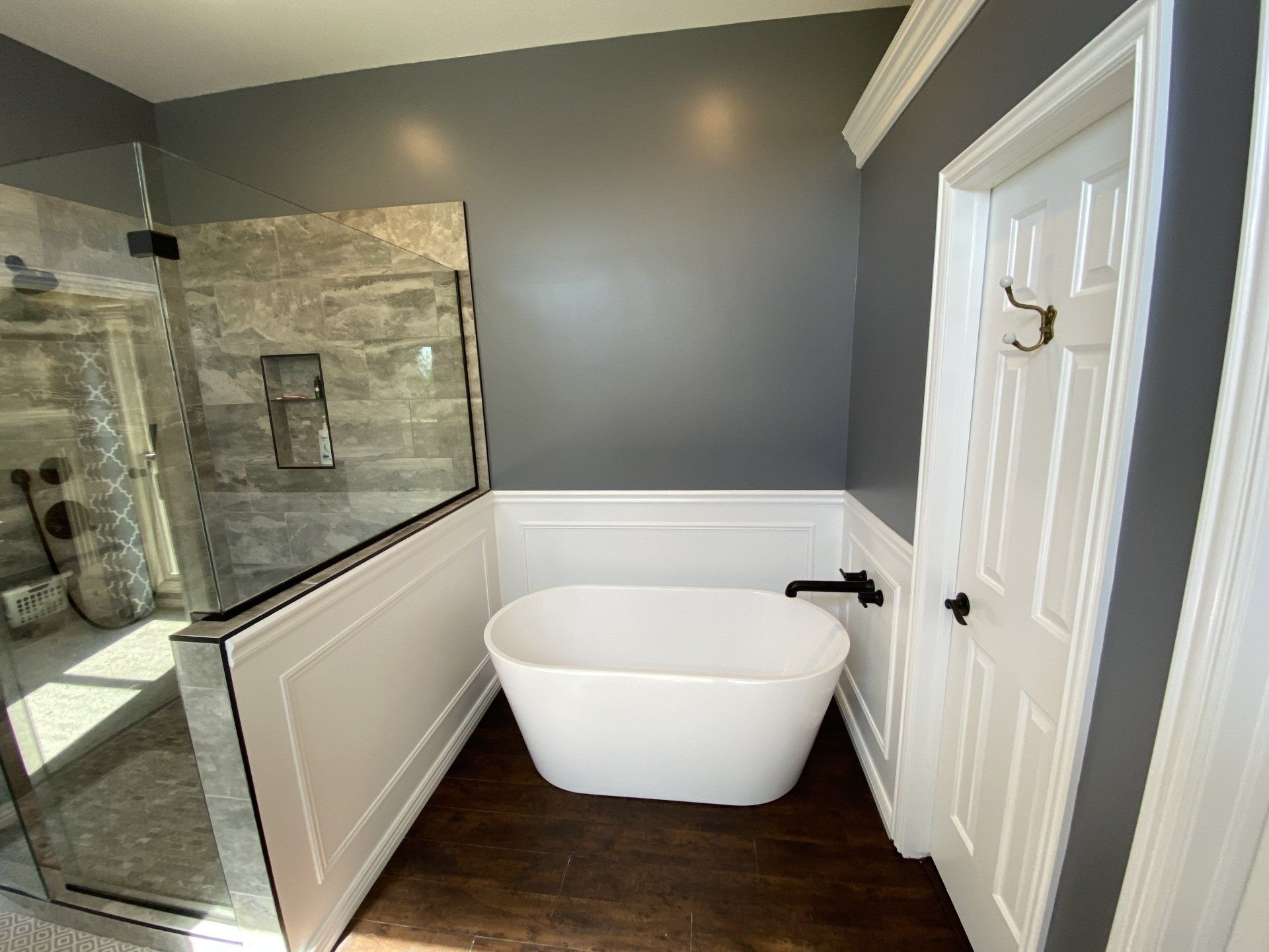 Modern bathroom with a white freestanding tub, glass shower, and gray walls.