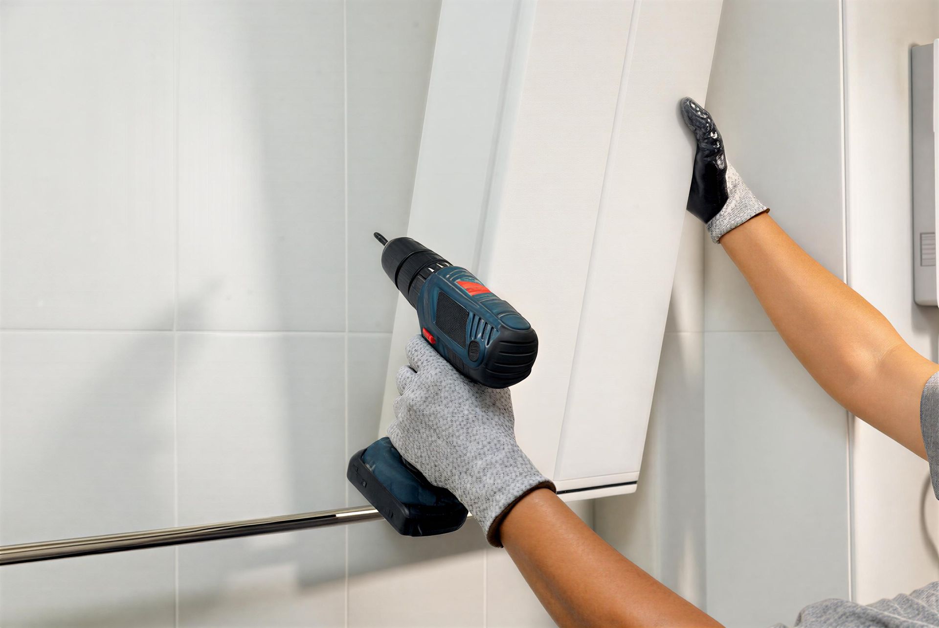 Handyman installing cabinet on bathroom wall. Handyman installing cabinet on bathroom wall.