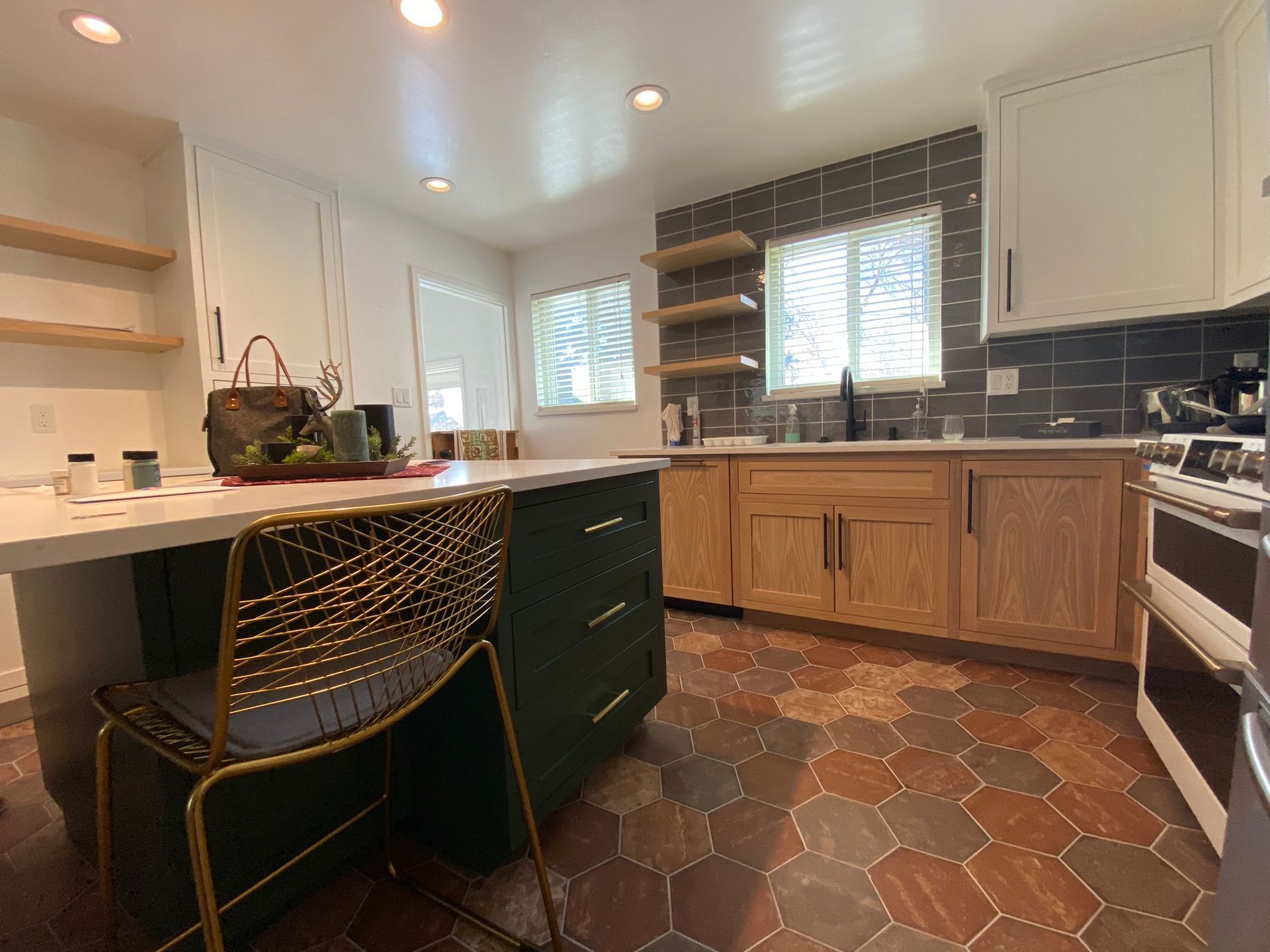 Kitchen with hexagon tile floor, green island, and light wood cabinets.
