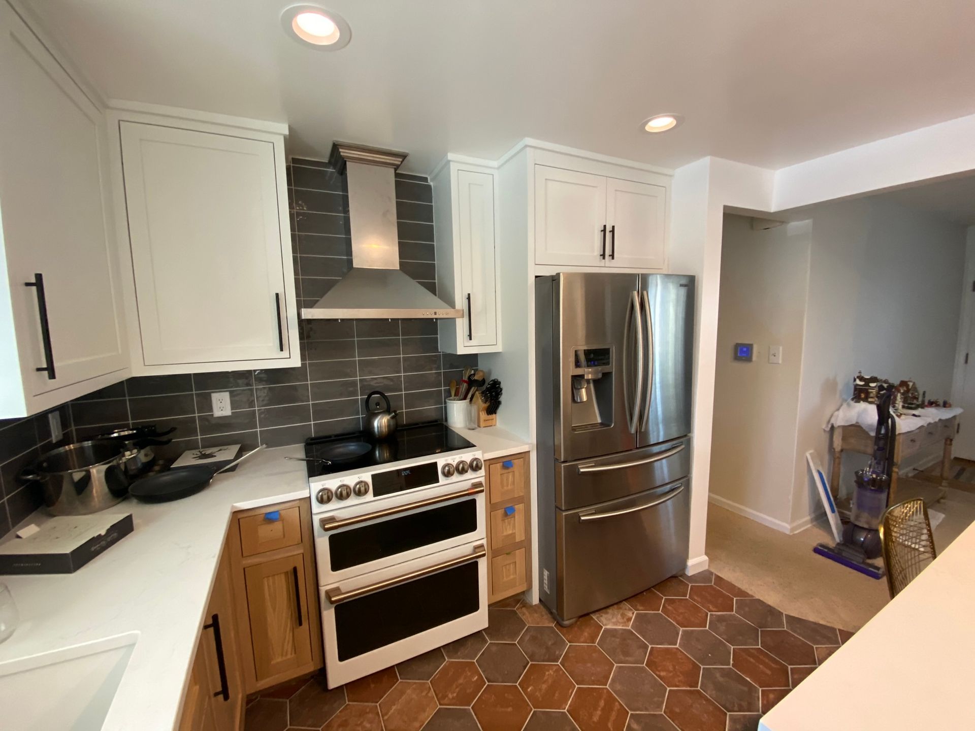 Kitchen with white and wood cabinets, stainless steel appliances, and dark tile backsplash.