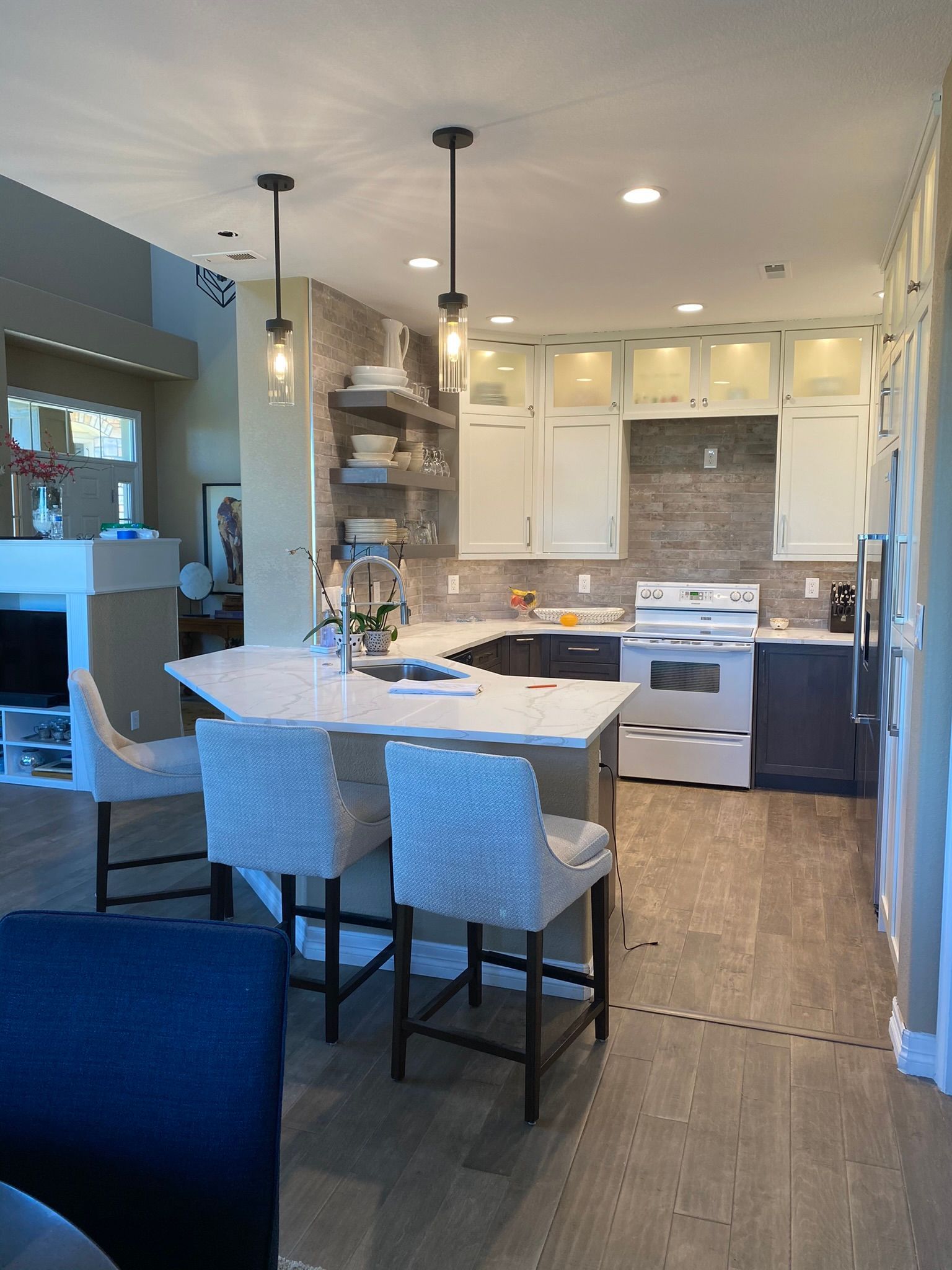 Modern kitchen with white cabinets, gray backsplash, island with seating, and pendant lights.